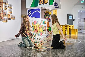 Jugendliche mit Mikadostäben und Spielkarten in Übergröße